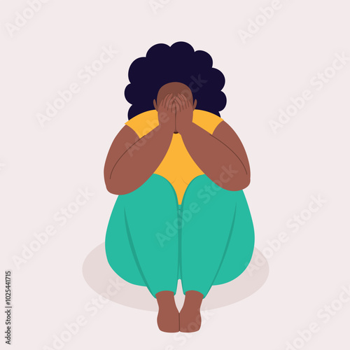 Front View Of One Overweight Black Woman Covering Her Face With Both Hands While Sitting On A Floor.