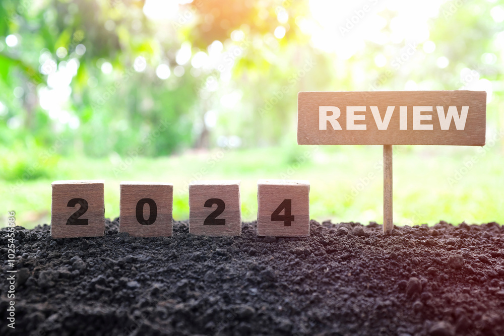 Year end 2024 review and summary concept. Wooden blocks in dark sunset on natural background.