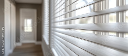 Close-up of white blinds with a blurred hallway in the background.