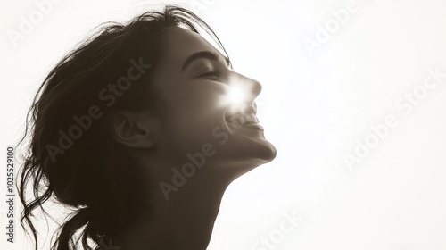 A close-up profile of a woman with her eyes closed and a big smile, the sun shining behind her.