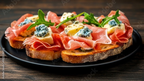 Close-up of three crostini topped with prosciutto, blue cheese, and arugula on a black plate.