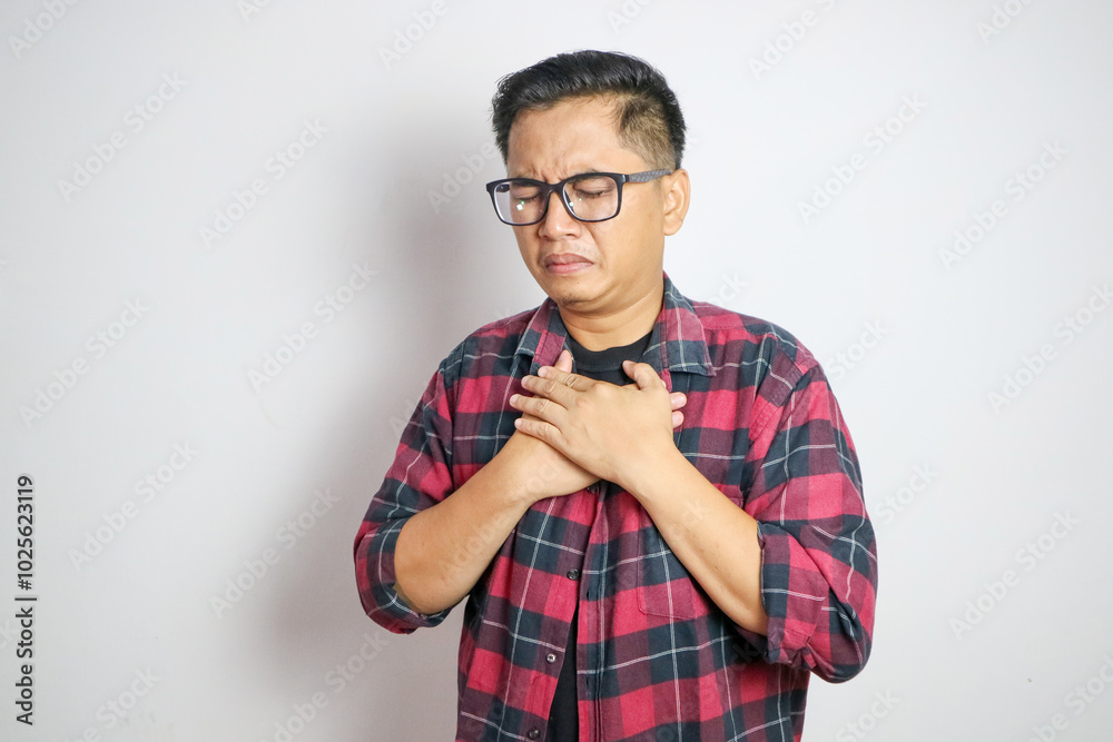hand hold chest with heart attack symptoms, asian man working hard have chest pain caused by heart disease, leak, dilatation, enlarged coronary heart, press on the chest with a painful expression hand hold chest with heart attack symptoms, asian man working hard have chest pain caused by heart disease, leak, dilatation, enlarged coronary heart, press on the chest with a painful expression