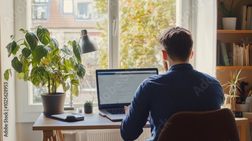 Man Working on Laptop at Home with Plants and Window View