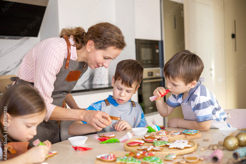 Happy family mother and children in aprons making Christmas cookies together while cooking Happy family mother and children in aprons making Christmas cookies together while cooking
