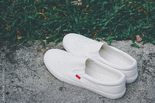 White canvas sneakers slip on men's footwear fashion on cement floor outdoor. photo