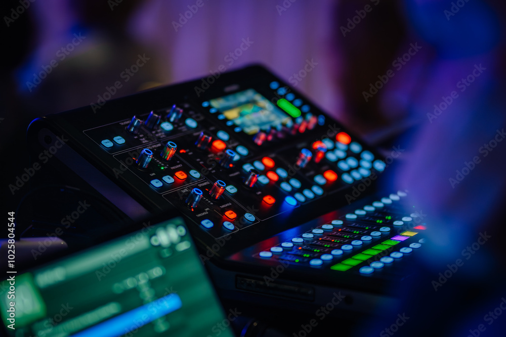 Obraz premium A close-up of an audio control panel with colorful illuminated buttons and knobs, capturing the details of a live event’s audio mixing equipment..