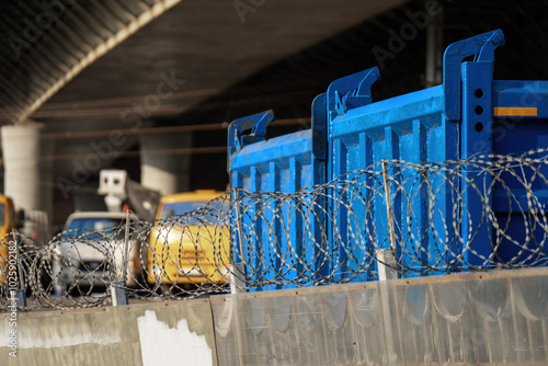 glimpse into industrial resilience, this photograph showcases heavy-duty trucks behind a sturdy fence, reinforced by an armored steel tape, symbolizing protection and strength photo