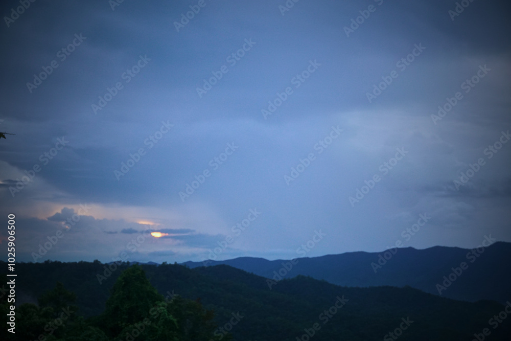 The sky is dark and cloudy, with a bright sun peeking through the clouds The sky is dark and cloudy, with a bright sun peeking through the clouds