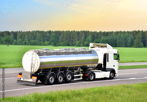 Isothermal Tank truck driving on highway. Oil and Gas Transportation and Logistics. Metal chrome cistern tanker with petrochemicals products. Liquid Chemical Freight. Soft focus possible granularity photo