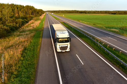 Truck with semi-trailer driving along highway on the sunset background. Goods delivery by roads. Services and Transport logistics. Soft focus.