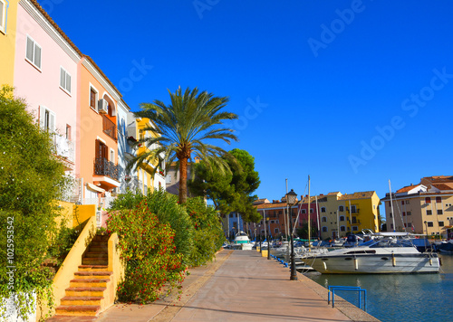 Yacht near Jetty. Yachts and motor boats in marina Port Saplaya, Valencia. Yacht and fishing motorboat in yacht club. Colourful houses with apartments at coast Mediterranean Sea. Sailboat near pier. photo