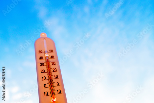 Thermometer for measuring outdoor air temperature. Meteorological device for observing and measuring the weather. Weather forecast. Thermometer on blue sky background. Hot weather, drought in summer.