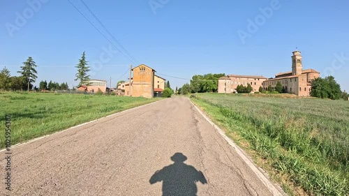 Via Francigena - a paved road entering Castione Marchesi with a view to Santa Maria Assunta Abbey, Fidenza, province of Parma, Emilia-Romagna, Italy photo