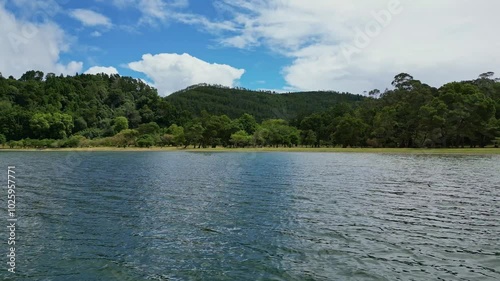 Aerial drone video of beautiful Furnas crater lake, mountains and trees. Camera flies low above the water, then up above the trees. Travel destination. Sao Miguel Island, Azores, Portugal photo