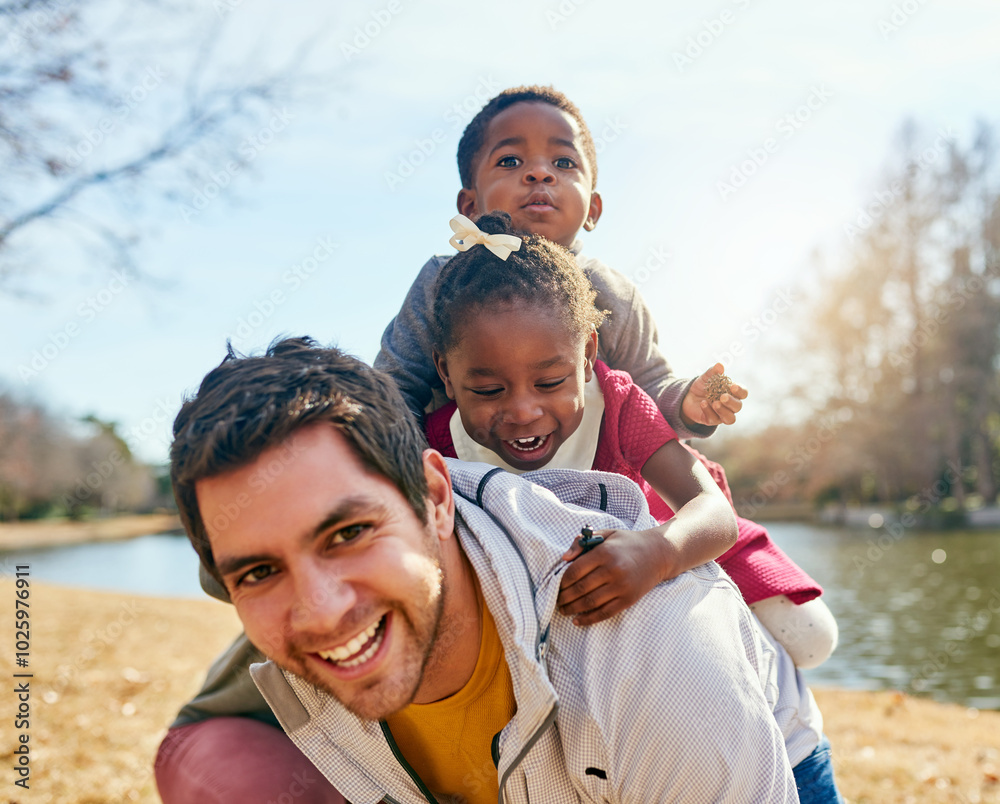 Fototapeta premium Father, children and adoption with piggyback, smile and field for fun and playing in park. Vacation, interracial family and kids with bonding, carry and joy together for summer holiday confidence