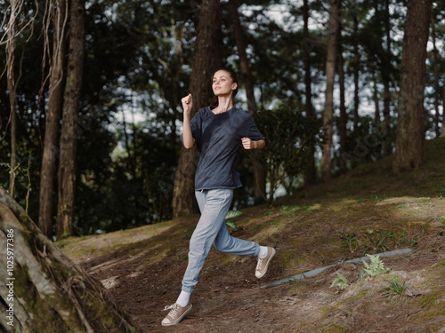 Energetic young woman running through a wooded area, embracing fitness and well being with a joyful expression Nature and outdoor activity concept