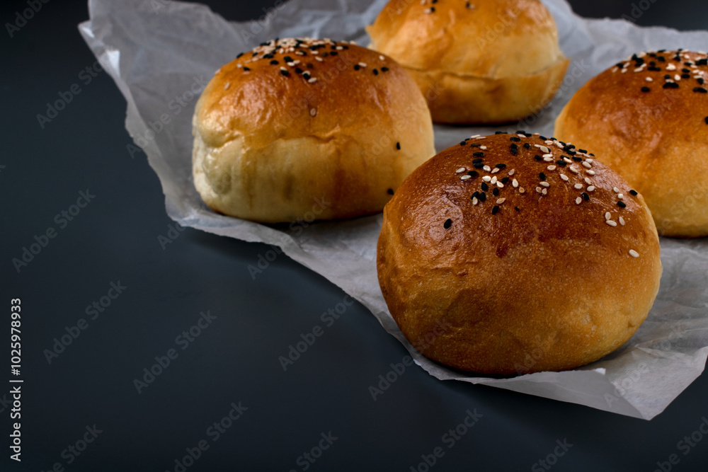 Yeast buns with sesame seeds on a gray background. Homemade bakery product. Copy space Yeast buns with sesame seeds on a gray background. Homemade bakery product. Copy space