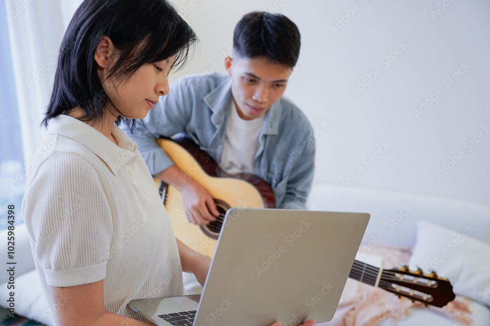 Two Asian people learning guitar at home Two Asian people learning guitar at home