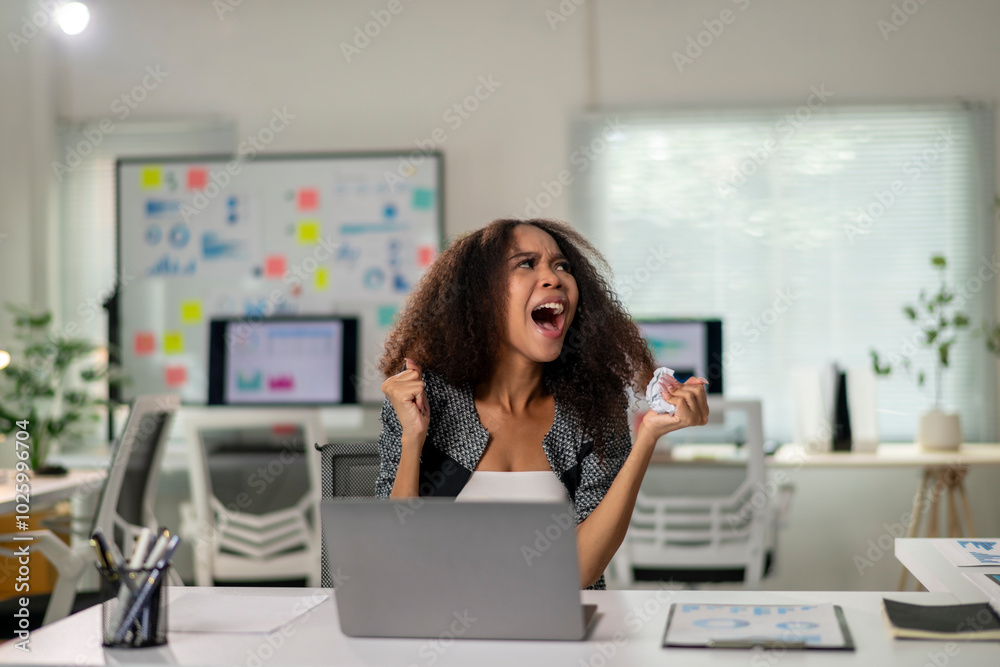 A woman is sitting at a desk with a laptop and a stack of papers A woman is sitting at a desk with a laptop and a stack of papers