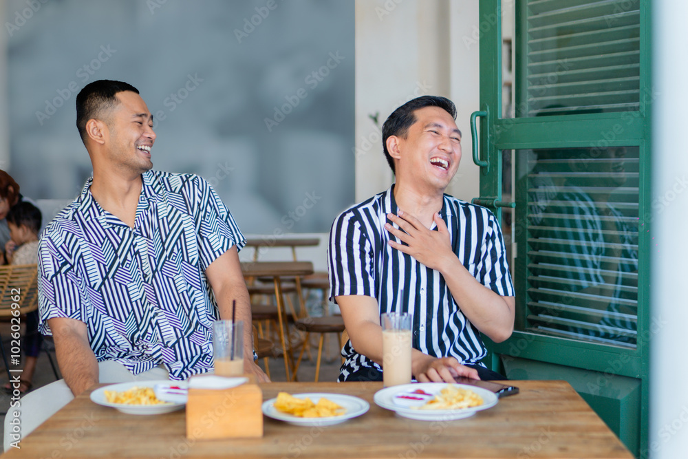 Two friends laughing together over breakfast in a bright caf atmosphere Two friends laughing together over breakfast in a bright caf atmosphere