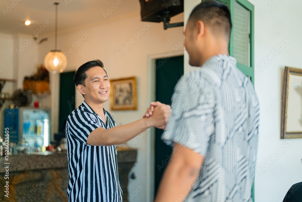Two men share a friendly handshake in a stylish cafe, fostering connection and camaraderie Two men share a friendly handshake in a stylish cafe, fostering connection and camaraderie