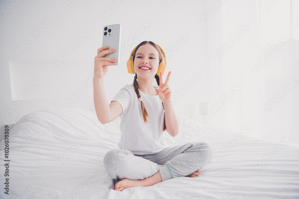 Portrait of cheerful joyful lovely girl sitting bed recording video v-sign webcam call cosy room white light interior indoors Portrait of cheerful joyful lovely girl sitting bed recording video v-sign webcam call cosy room white light interior indoors