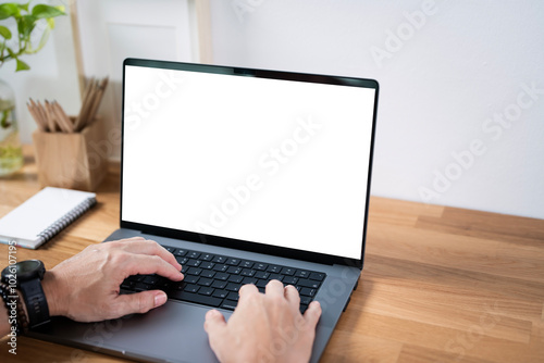 Wallpaper Mural Close-up image of a man working on laptop computer at a table, typing on the laptop keyboard. the laptop with a white screen mockup Torontodigital.ca