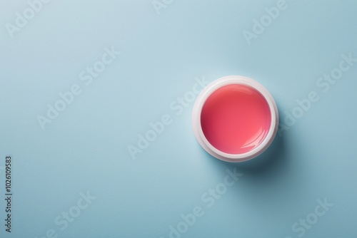 Soft pink lip balm in a white container on a light blue background photo