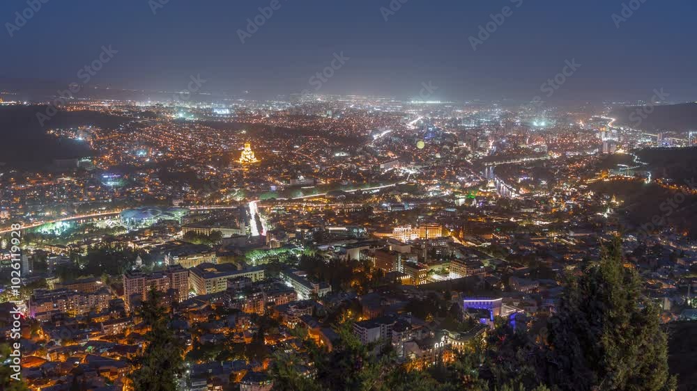 Tbilisi cityscape at twilight, Georgia day to night transition timelapse. Top view over the city center and Kura river in Tbilisi. Aerial view of the Georgian capital from above after sunset