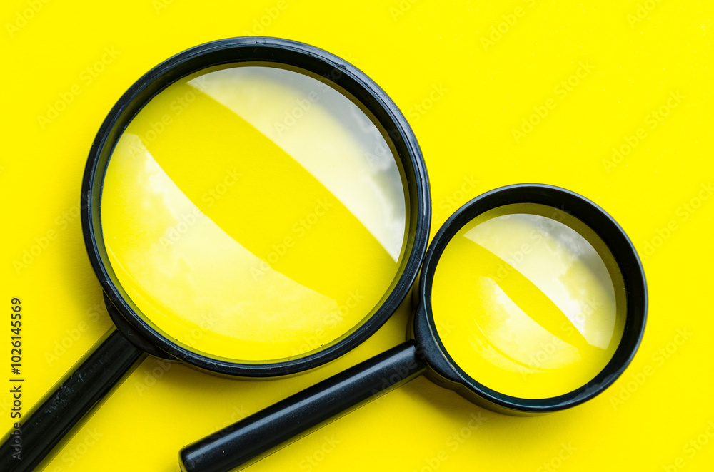 Two magnifying glasses on yellow cover background with customizable space for text or ideas Two magnifying glasses on yellow cover background with customizable space for text or ideas