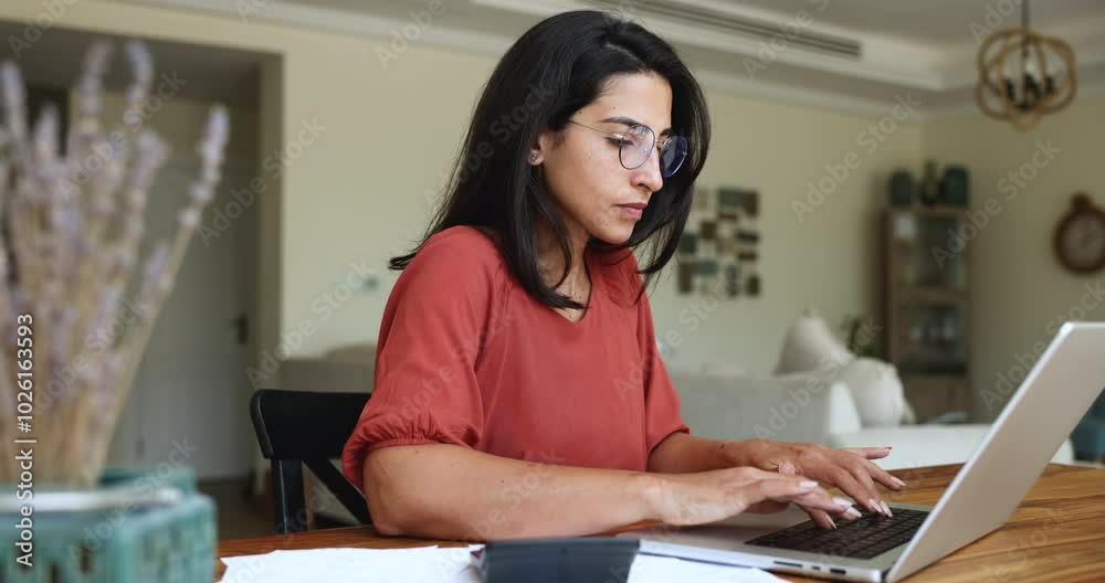 Woman working on laptop, sit with documents and calculator on table, working from home, managing personal finances, review receipts, counts sum to pay, checking bills, making financial transactions