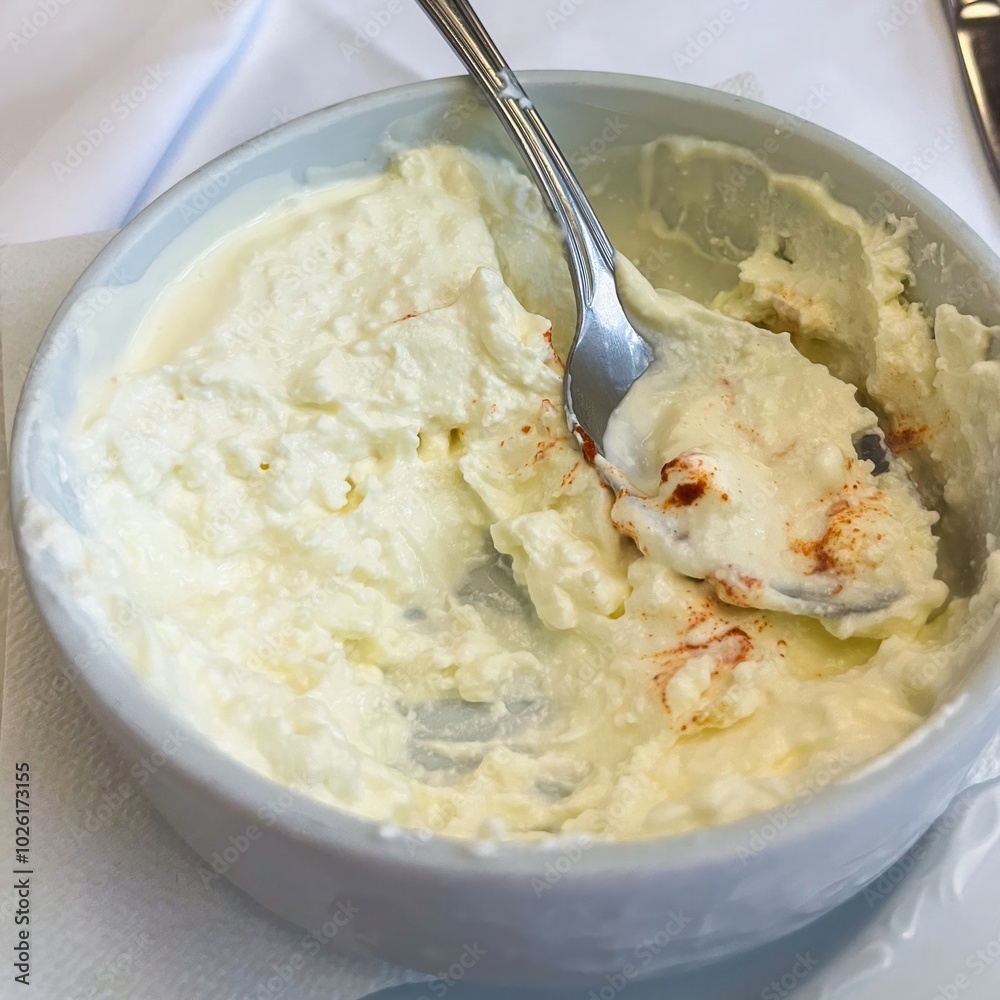 White soft curd cheese in a plate with a spoon