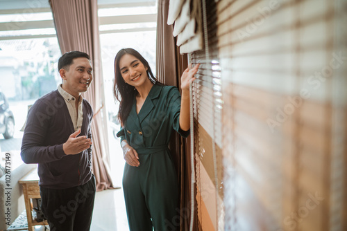 asian male customer paying attention to the beautiful shopkeeper while explaining the different types of blinds at their store photo