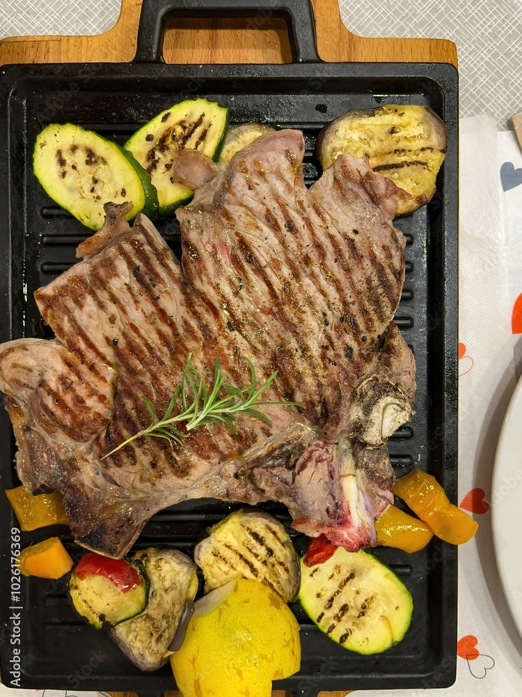 grilled ribs with vegetables and lemon on the table on a cast iron tray