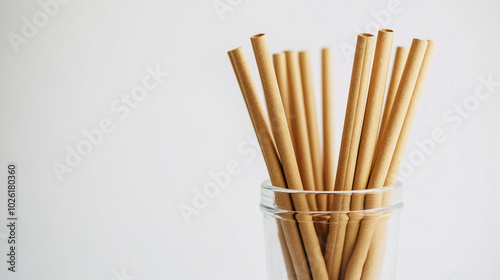 Natural paper straws arranged in a glass on a plain background in a kitchen setting