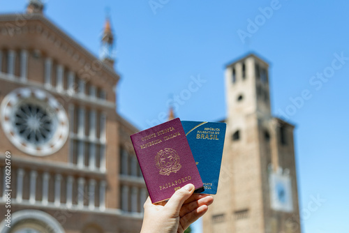 Hand holding Italian and Brazilian passports in a historic Italian cityscape, symbolizing dual citizenship