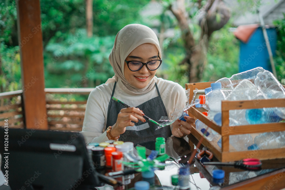 asian hijab woman painting recycled plastic bottle waste