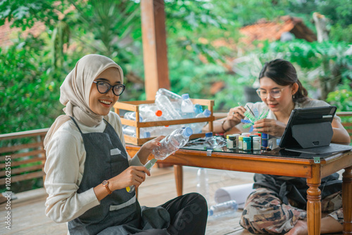 asian hijab woman making craft made from plastic bottle waste with friend