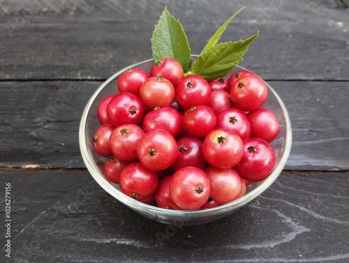 Muntingia calabura or cherries in a bowl on the black wooden table  photo