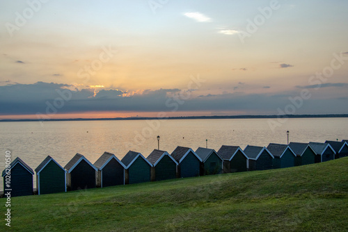 Beach huts at Gurnard, Cowes, Isle of Wight at sunset.  Looking over the western Solent