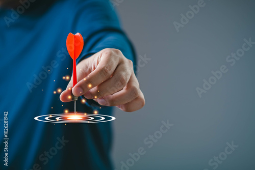 Hand aiming a dart at a glowing target, symbolizing focus, precision, and success in achieving goals