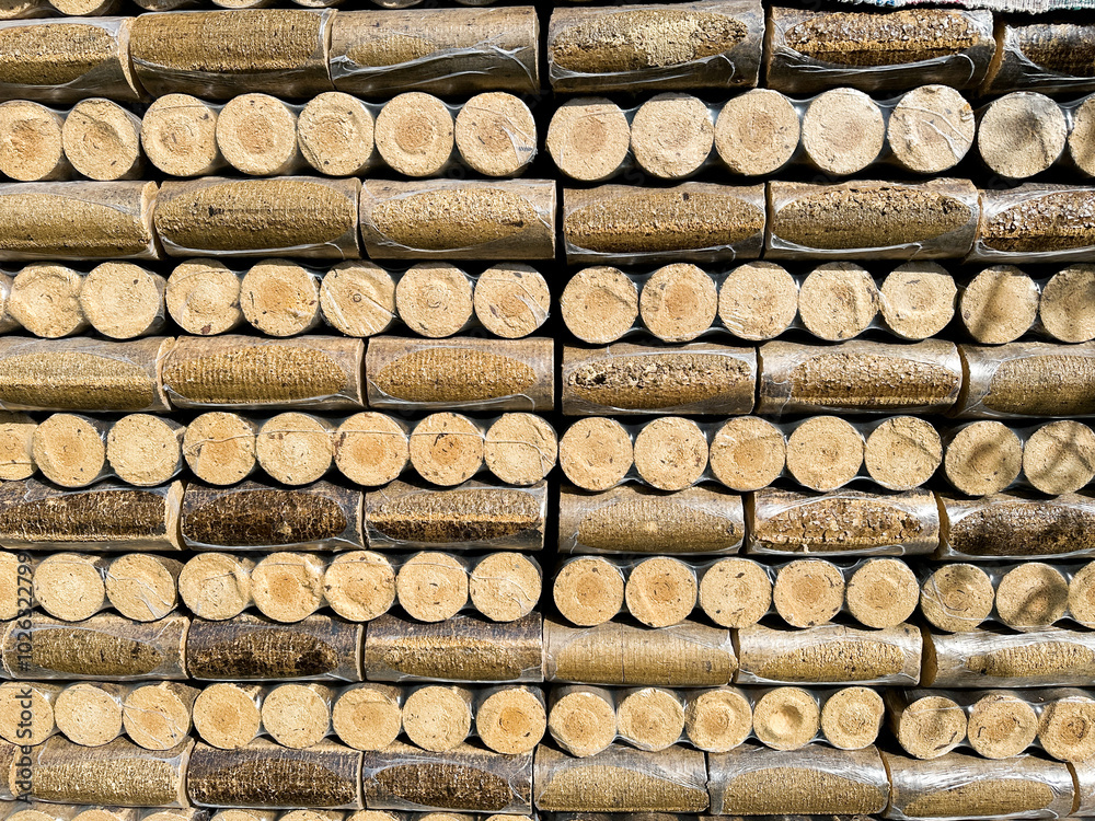 A stack of compressed wood logs sits outside, ready to be used for a fire A stack of compressed wood logs sits outside, ready to be used for a fire