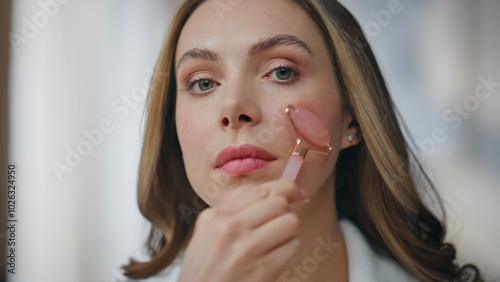 Woman using natural massager looking camera at bedroom portrait. Lady skincare