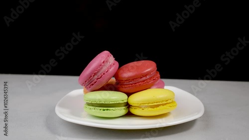 Sweet and multi-colored french macaroons on a black background.