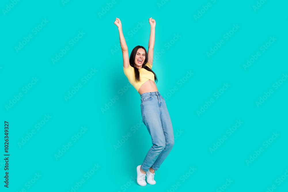 Full size photo of nice young woman raise fists wear top isolated on teal color background Full size photo of nice young woman raise fists wear top isolated on teal color background