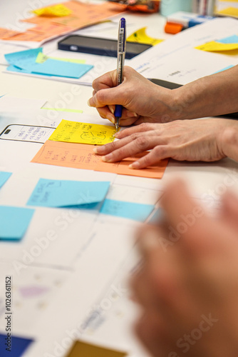 Collaborative Brainstorming with Sticky Notes. Close-up of hands actively participating in a brainstorming session. photo