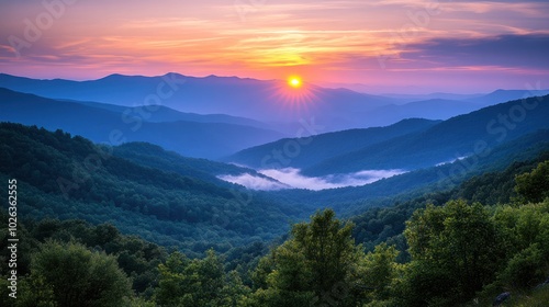A vibrant sunset casts a golden glow over a mountain range, with layers of hills receding into the distance.