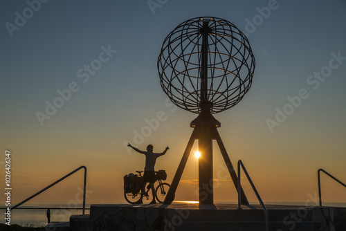Silhouette eines Radfahrers mit dem Globus am Nordkap in Norwegen