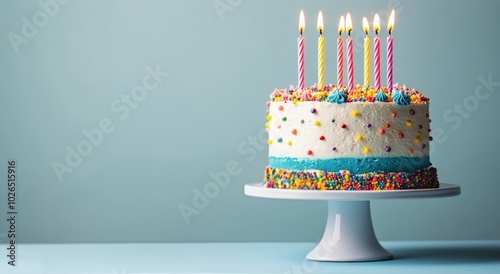 Colorful birthday cake with candles and sprinkles on a light blue background