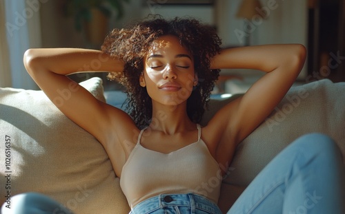 Relaxing in natural light, a young woman enjoys a peaceful moment on a cozy sofa